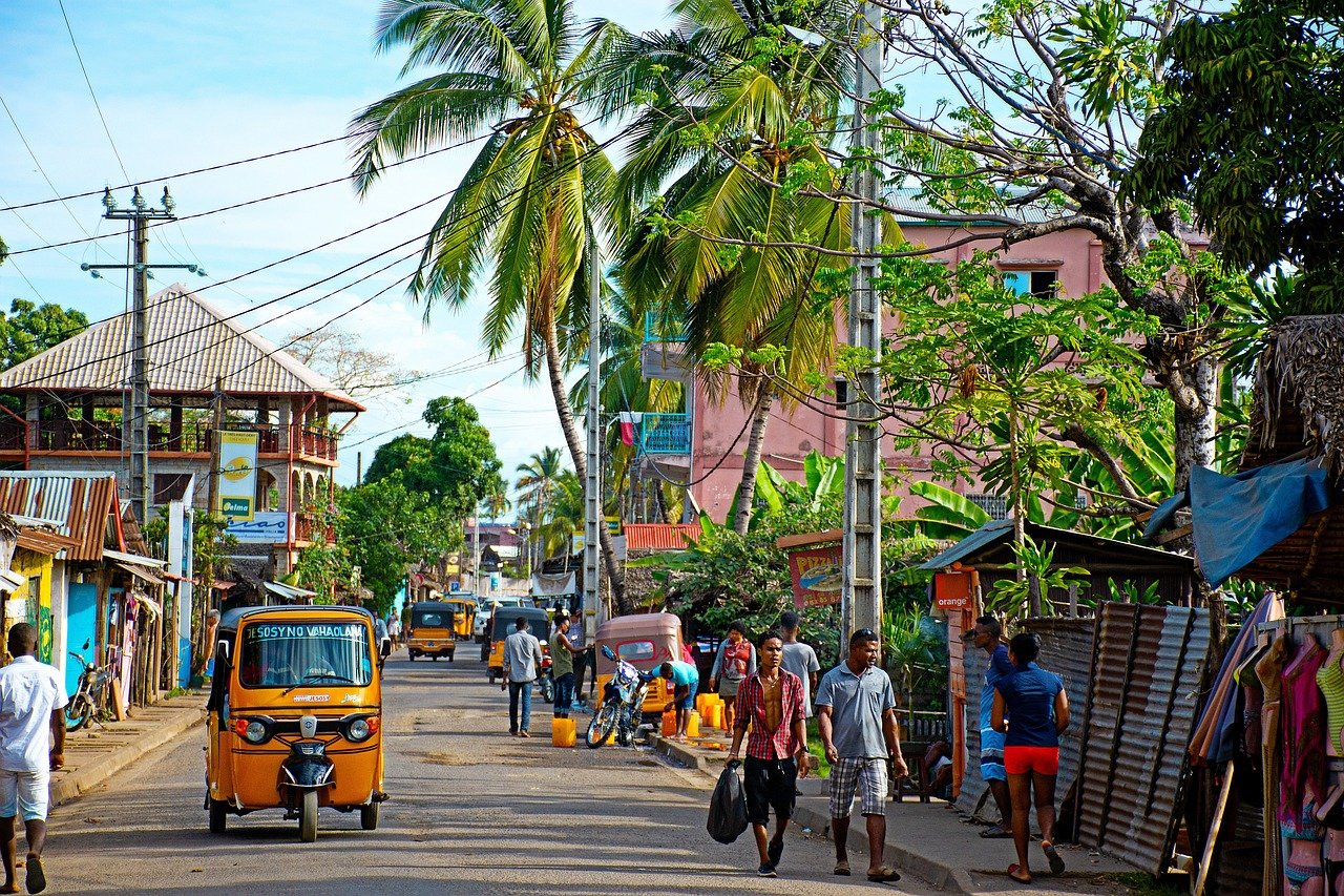 Scène de rue avec des tuk-tuks, des maisons et des palmiers à Madagascar